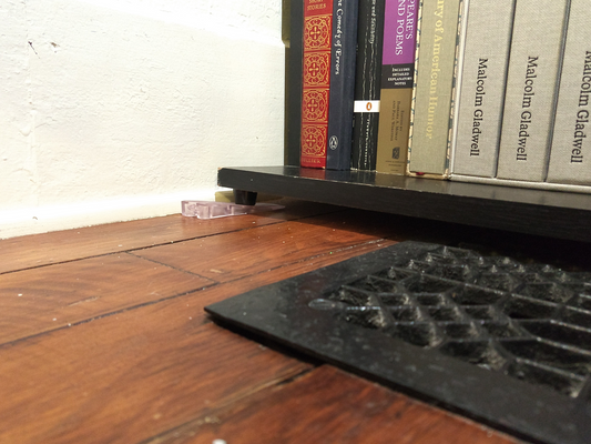 Plastic Furniture Leveler under a bookcase foot to bring it to level