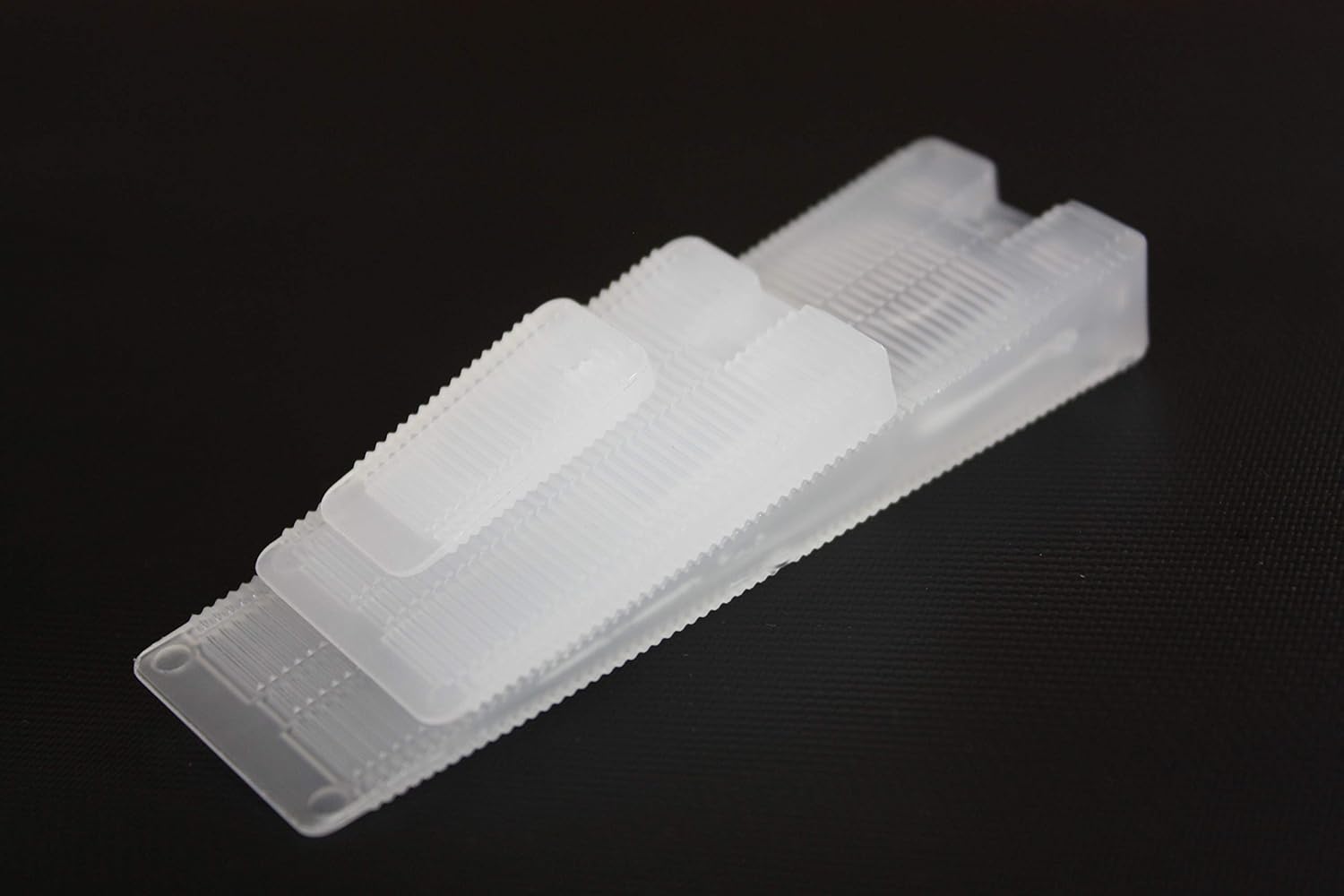 Stacked clear wedges in different sizes on a black background.