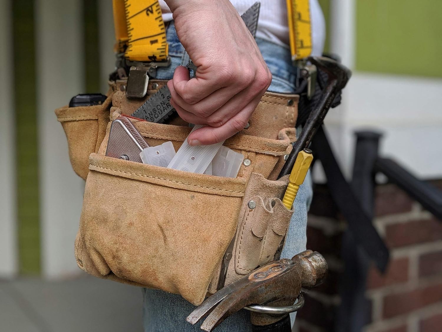 Person wearing a tool belt outdoors with hand tools and clear Wobble Wedges